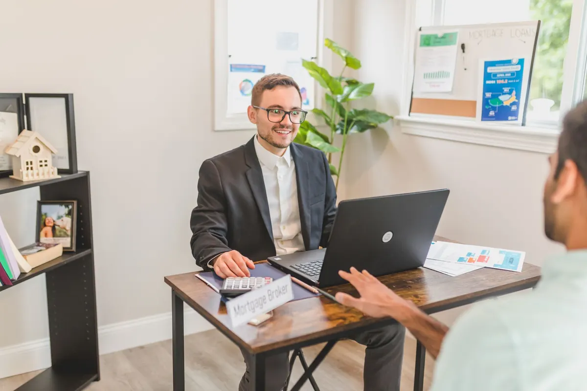 Adviseur in gesprek met een cliënt aan een bureau met laptop