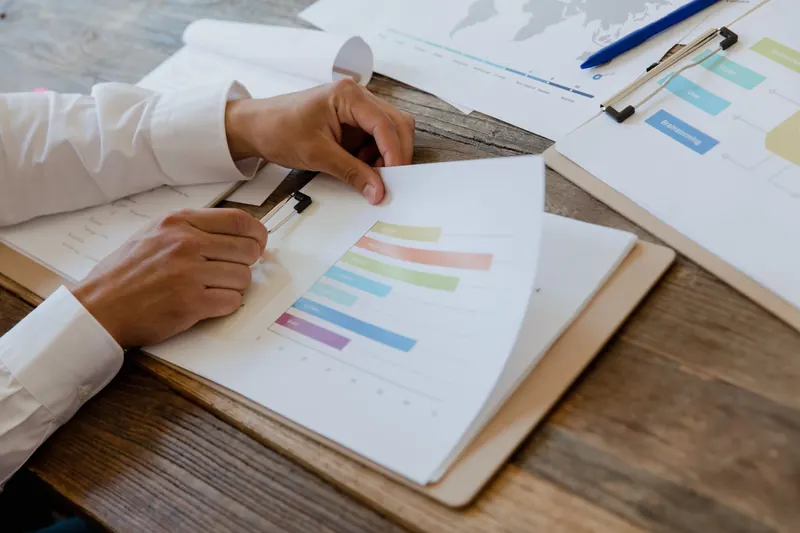 Handen bij een rapport met kleurrijke grafieken op een houten bureau