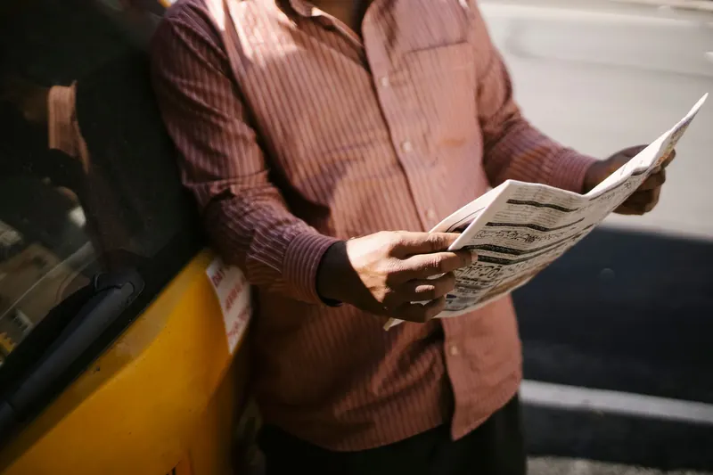 Man met een opengeslagen krant in de zon