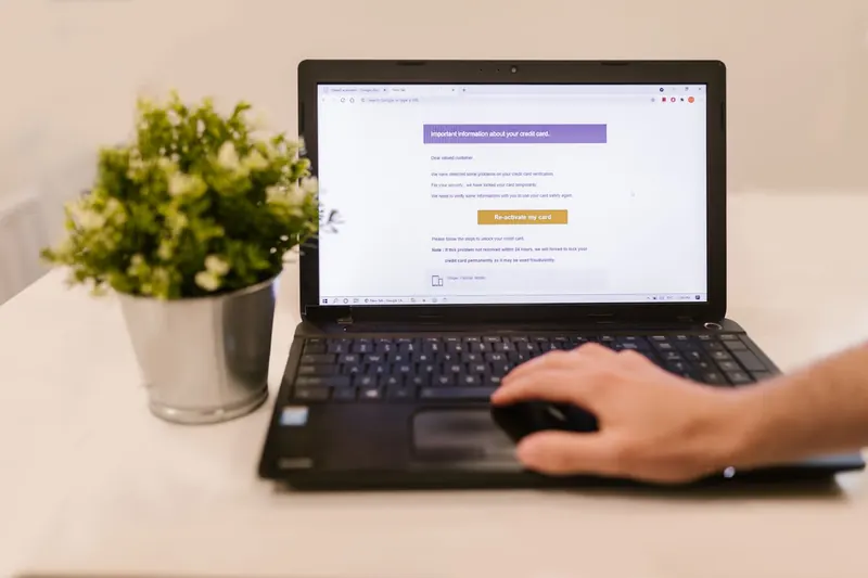Persoon gebruikt een laptop aan tafel naast een plant