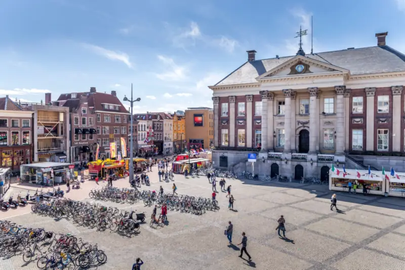 Stadhuis aan de Grote Markt in Groningen met fietsers en voetgangers