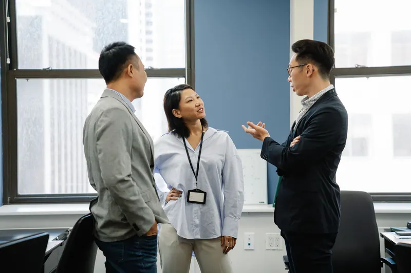 Drie collega's in gesprek op kantoor